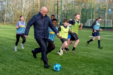 John Swinney Scottish first minister John Swinney playing football with some children